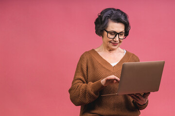Senior aged business woman with laptop. Grandmother isolated over pink background. - 578497294