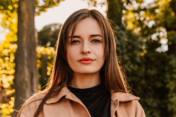 Caucasian young pretty stylish woman standing outside street dressed brown trench coat smiling...