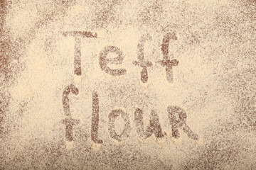 Organic Teff Flour scattered on brown surface with inscription Teff flour. Trendy Superfood. Design element