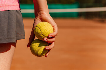 Caucasian woman hold yellow green balls, playing tennis match on clay court surface on weekend free...