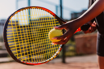 African american woman hold racket and yellow green ball, playing tennis match on clay court surface on weekend free time sunny day. Female player ready to serve. Professional sport concept
 - obrazy, fototapety, plakaty