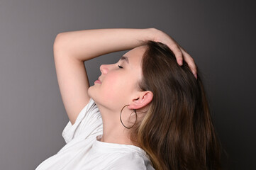 Portrait of a young beautiful teen model in white shirt on gray background. Teen face in profile
