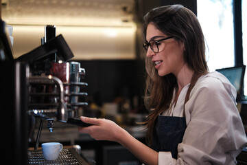 Barista standing in a coffee shop and making espresso on a coffee machine.