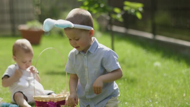 funny Easter boy wear bunny ears jumping on green grass. traditional family Easter picnic sunny day in park or backyard. children have fun Easter holidays outdoor. Easter activities for kids