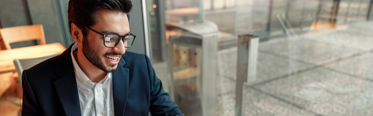 Indian businessman is making notes in notepad during working day in cafe. Blurred background
