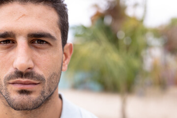 Portrait of happy biracial man looking at camera and smiling at beach, with copy space