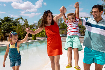 Happy biracial family walking and holding hands by the swimming pool - Powered by Adobe