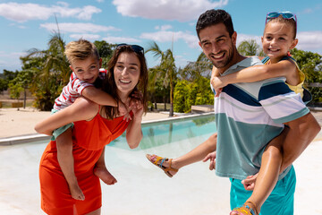 Portrait of happy biracial family smiling by the swimming pool - obrazy, fototapety, plakaty