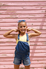 Portrait of happy biracial girl smiling and showing muscles over pink wall - obrazy, fototapety, plakaty