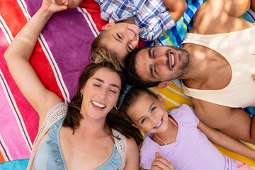 Portrait of happy biracial family lying on towel at beach