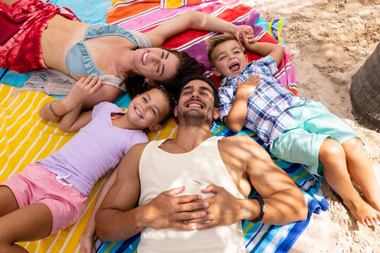 Portrait of happy biracial family lying on towel at beach