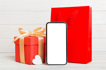 mobile phone with blank screen on colored background with hearts, calendar and gift box, valentine day concept perspertive view flat lay