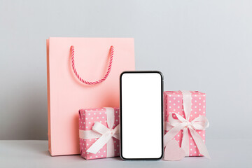 mobile phone with blank screen on colored background with hearts, calendar and gift box, valentine day concept perspertive view flat lay