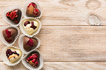 chocolate sweets in the form of a heart with fruits and nuts on a colored background. top view with space for text, holiday concept