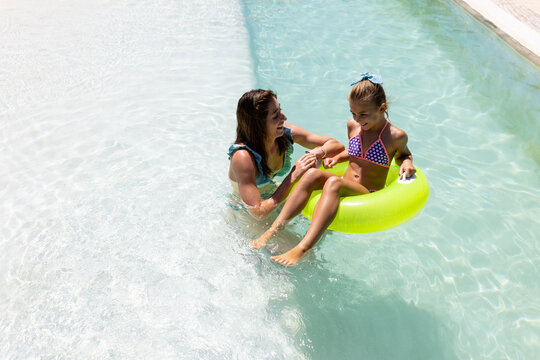 Happy biracial mother and daughter playing together in swimming pool