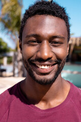 Portrait of happy african american man looking at camera and smiling at beach