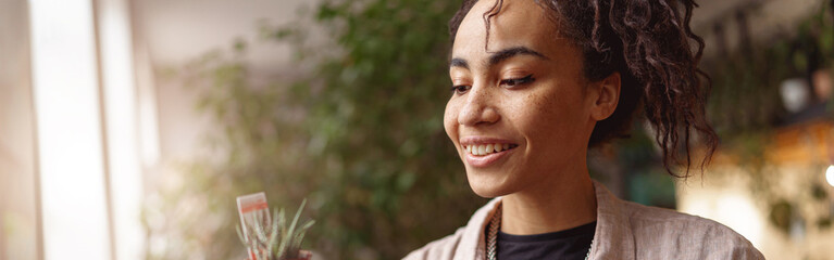 Obraz premium Woman florist takes care of seedlings in floral studio. Gardening concept. Blurred background