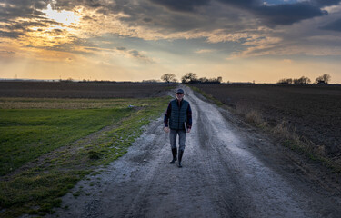 Obraz premium Senior farmer walking on dirty road