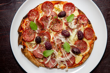 Traditional rustic pizza with pepperoni, black olives, onion and basil