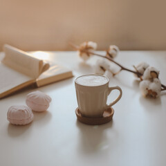 coffee cup, flower, candle and a book on a white table background top view. minimal home interior decor