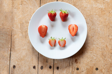 Juicy ripe fresh homegrown red strawberries on a white plate on rustic wooden table