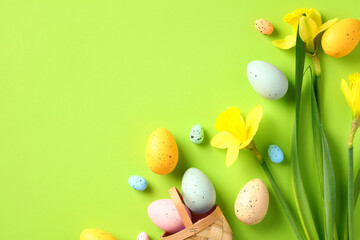 Happy Easter greeting card template. Flat lay composition with colorful Easter eggs and yellow daffodil flowers on green background.