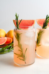 Honey Rosemary Grapefruit Sodas Garnished with Red Grapefruit: Nonalcoholic sodas served in can-shaped glasses with ice cubes