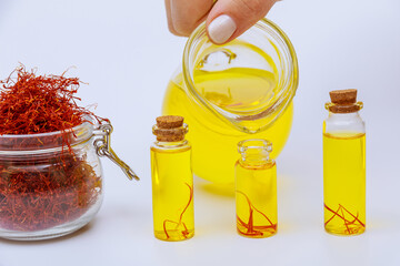 Pouring saffron tinctures into glass jars on a white background. Dry saffron stamens.
