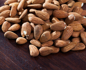 Fototapeta premium Heap of roasted almonds on wooden surface