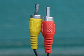 two old colored electrical plugs with black wires on a green background