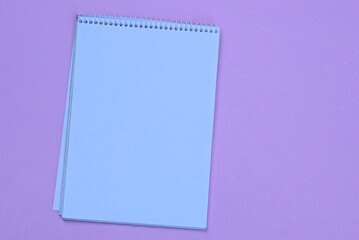 one white empty open notebook lies on a pink table