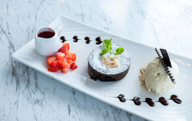 Chocolate fondant lava cake with strawberries and vanilla ice cream in a plate