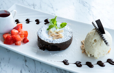 Chocolate fondant lava cake with strawberries and vanilla ice cream in a plate