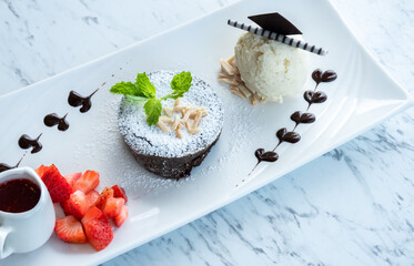 Chocolate fondant lava cake with strawberries and vanilla ice cream in a plate