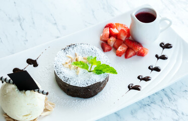Chocolate fondant lava cake with strawberries and vanilla ice cream in a plate