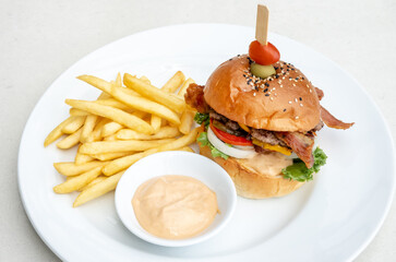 Single cheeseburger with bacon and French fries on table