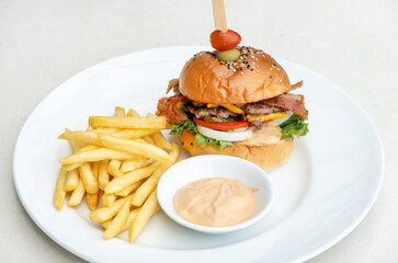 Single cheeseburger with bacon and French fries on table