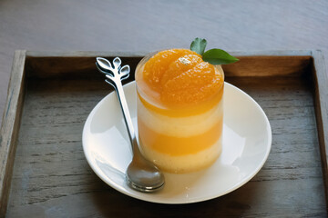 Orange cake and spoon in plate on wooden background