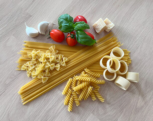 Arrangement of pasta and uncooked ingredients on wood table 