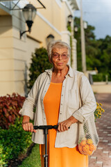 Stylish dressed eldery women in orang dress on scooter