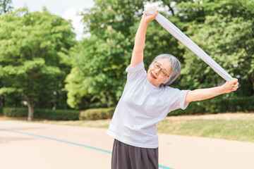 公園で運動・タオル体操するアジア人の高齢者女性（ヨガ・タオル）
