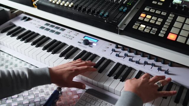 back view of a man playing an electronic piano with a sound synthesizer, music concept. High quality 4k footage