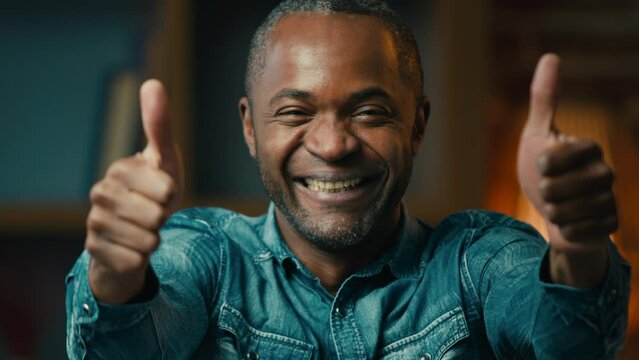 Mature satisfied african american man showing thumbs up at home gesturing approval sign like excellent result happy male homeowner smiling toothy smile show positive recommendation advertising concept