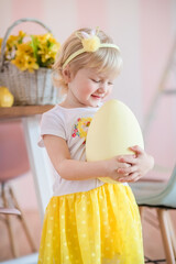 A little girl hunting for easter egg. A child in yellow clothes on Easter day found a painted egg