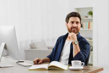 Home workplace. Happy man at wooden desk with computer in room