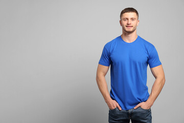 Man wearing blue t-shirt on light grey background. Mockup for design