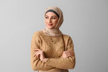 Stylish Muslim woman in beige hijab on light background