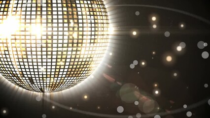 Animation of glowing spots of light over shiny golden disco ball spinning against black background - Powered by Adobe