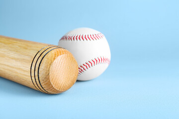 Wooden baseball bat and ball on light grey background, space for text. Sports equipment