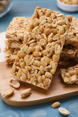 Delicious peanut bars (kozinaki) on light blue wooden table, closeup